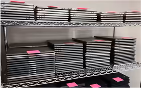 Shelves stocked with neatly organized stacks of decommissioned laptops.