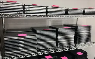 Shelves stocked with neatly organized stacks of decommissioned laptops.